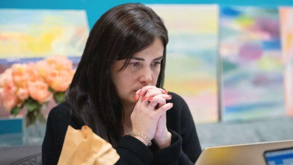 Tamara clasps her hands over her mouth, staring intensely at her laptop.